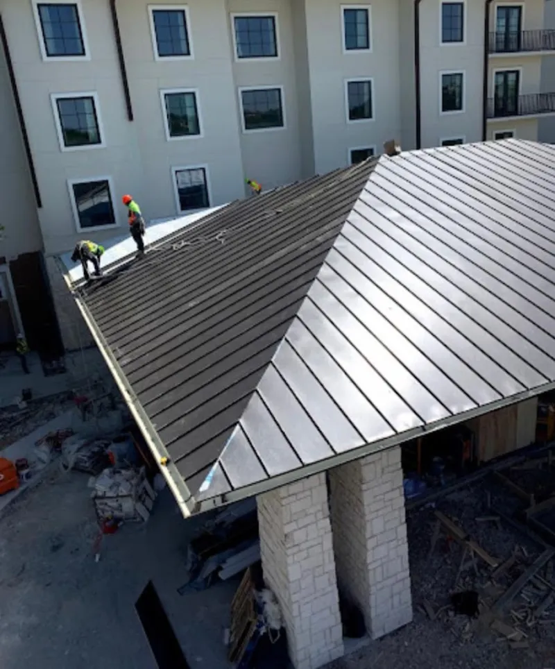 Crew installing standing seam metal roof panels on a commercial project in Kettering